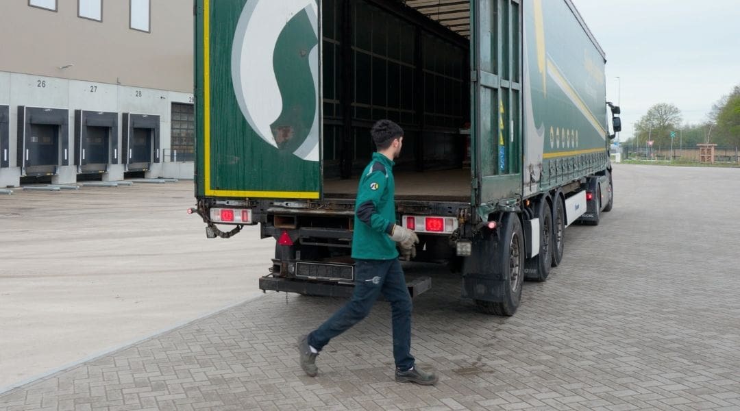 Medewerker loopt naar een open Sluyter-vrachtwagen op het terrein van de vestiging in Assen.